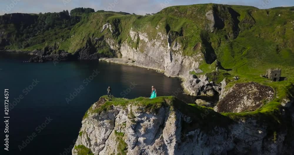 Rocky sea shore, photoshooting on top of a cliff with turquoise long dressed model at sunrise at Kinbane Castle, in Antrim coast, North Ireland