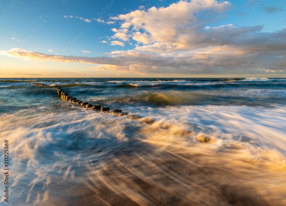 Obraz premium sunset over the sea beach in Poland, waves dynamically breaking into the beach