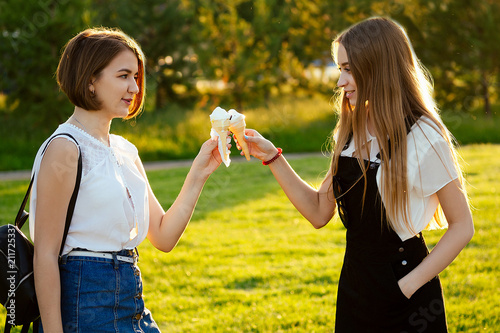 two beautifu best girlfriends schoolgirls   student  eating ice cream in a waffle horn in the park