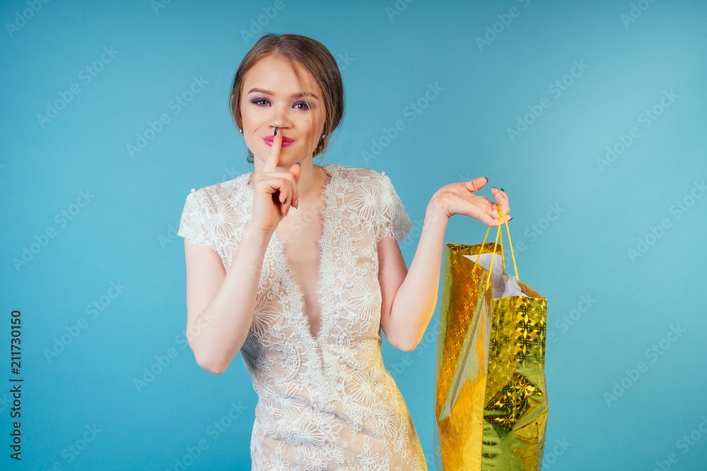 attractive shopaholic model beautiful woman bride with makeup in long chic sexy white wedding holding shopping bags in studio on a blue background. concept of shopping for a wedding party and prom attractive shopaholic model beautiful woman bride with makeup in long chic sexy white wedding holding shopping bags in studio on a blue background. concept of shopping for a wedding party and prom
