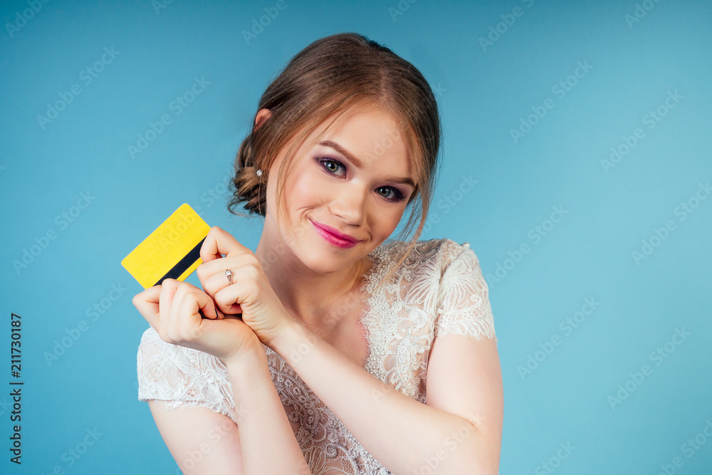 attractive shopaholic model beautiful woman bride with makeup in chic sexy white wedding holding credit card in studio on a blue background. concept shopping for a wedding party attractive shopaholic model beautiful woman bride with makeup in chic sexy white wedding holding credit card in studio on a blue background. concept shopping for a wedding party