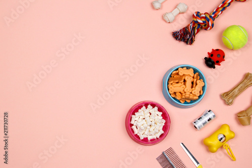 Dog accessories, food and toy on pink background. Flat lay. Top view.