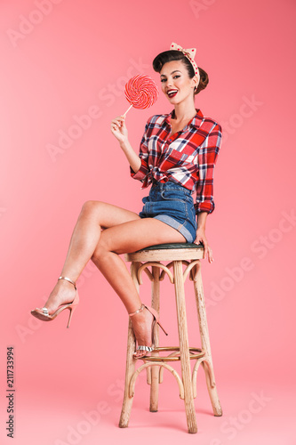 Beautiful young pin-up woman holding candy lollipop.