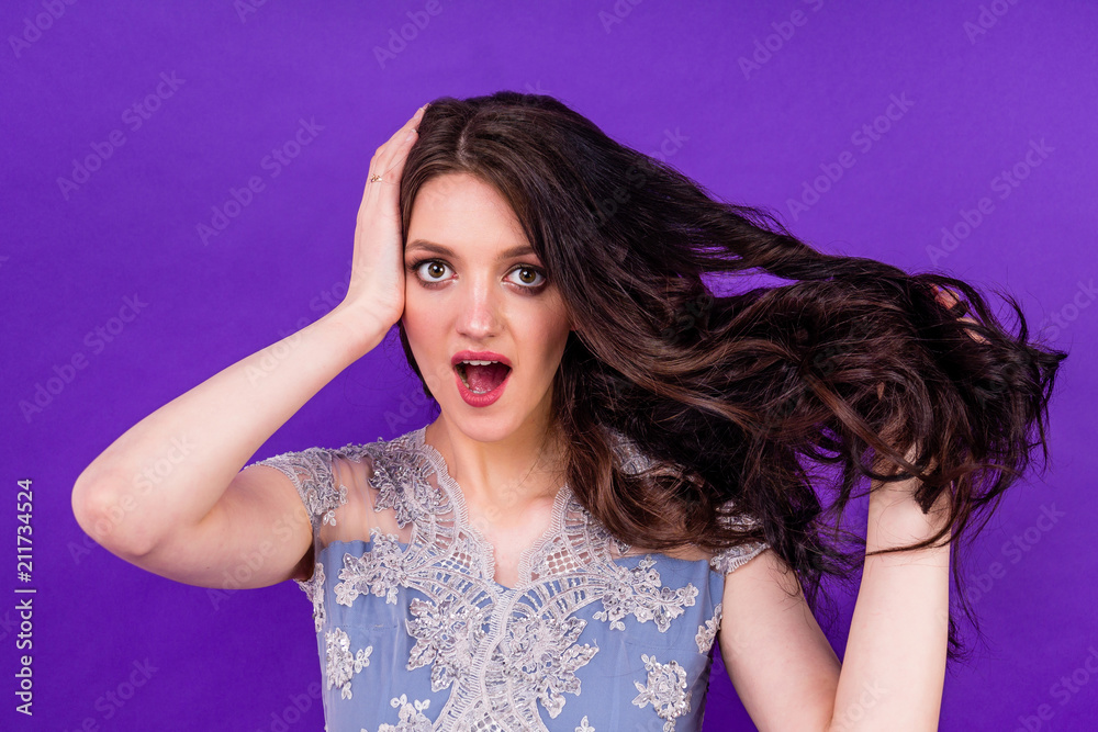 Indian panic woman in a wedding dress combs the tangled black long hair on a violet background in the studio