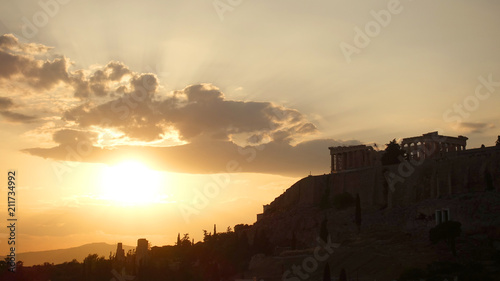 Iconic Acropolis hill and the Parthenon as seen from rooftop at sunset with golden colours and beautiful cloud formations, Athens historic center, Attica, Greece 