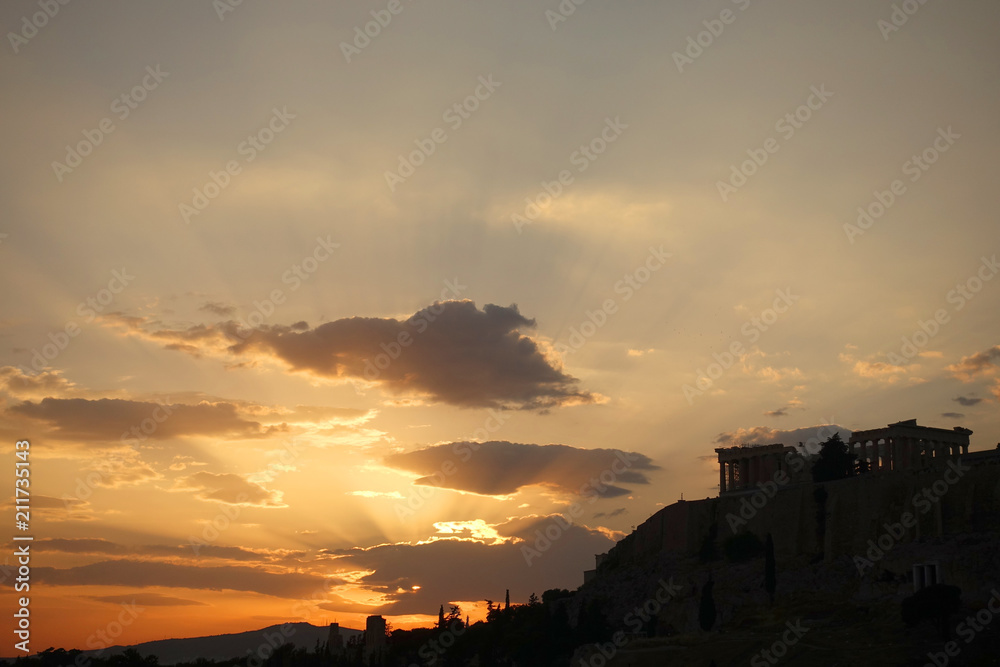 Iconic Acropolis hill and the Parthenon as seen from rooftop at sunset with golden colours and beautiful cloud formations, Athens historic center, Attica, Greece     