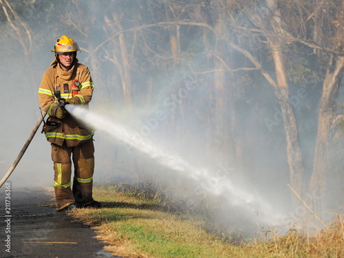 Melbourne, Australia - April 13, 2018: Fire fighter with a hose at a bush fire in an suburban area of Knox City in Melbourne east.