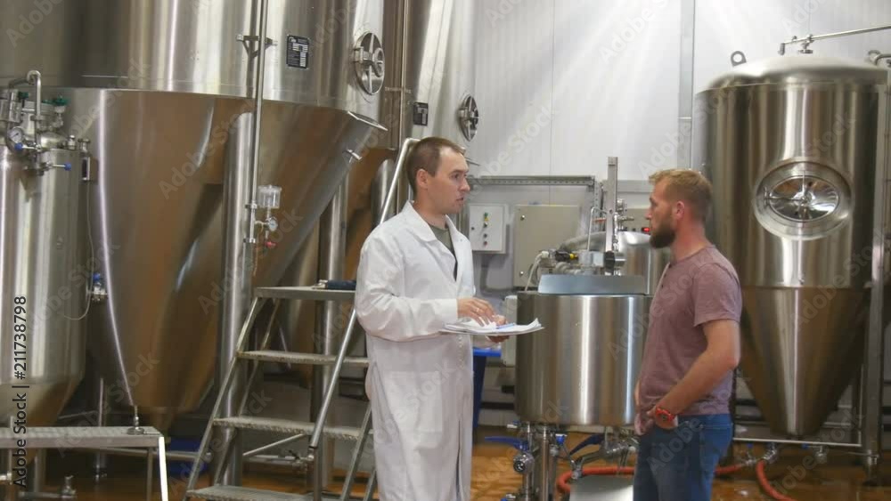 Men with clipboard working at brewery or beer plant Men with clipboard working at brewery or beer plant