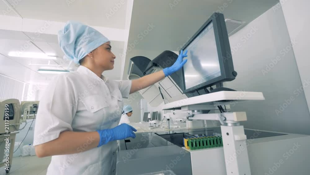 A nurse works with a monitor ina lab with a modern automated medical equipment. A nurse works with a monitor ina lab with a modern automated medical equipment.