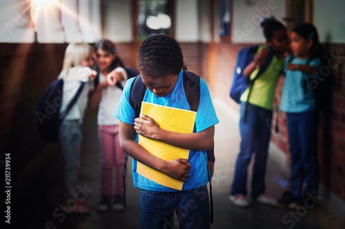 Sad pupil being bullied by classmates at corridor photo
