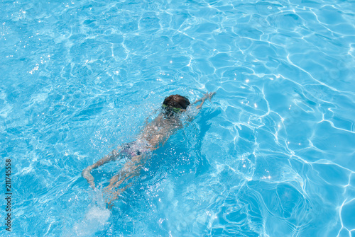healthy little boy diving in azure swimming pool in sunny summer day resort