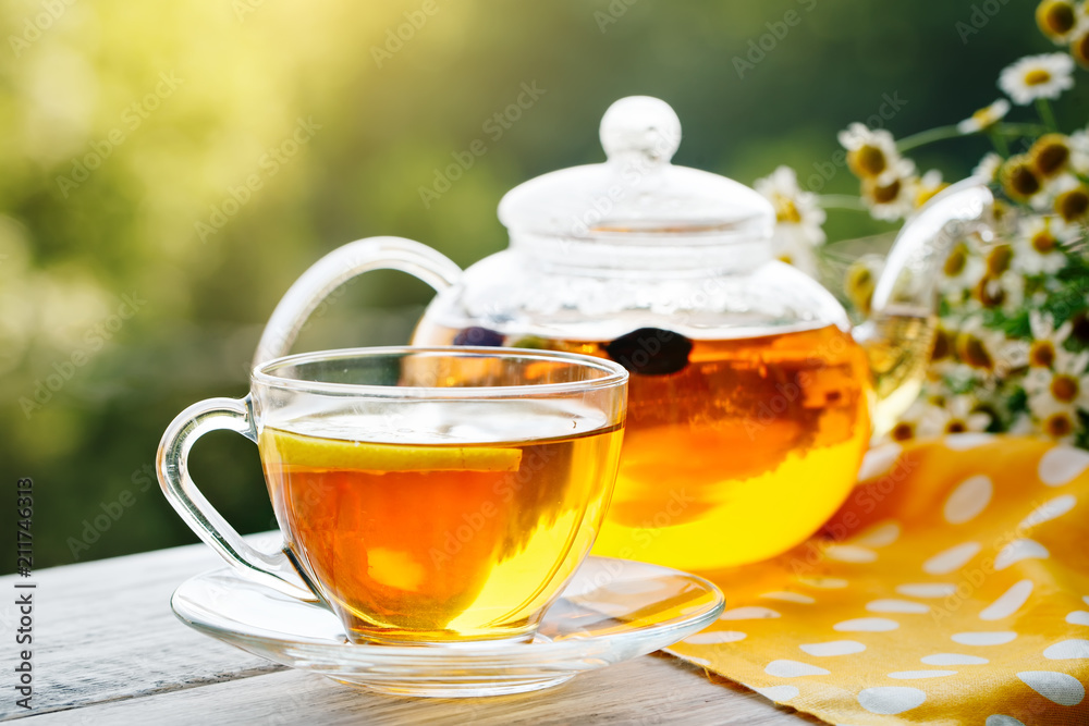 Cup with hot tea with mint and a thyme on a wooden table in a summer garden. Cup with hot tea with mint and a thyme on a wooden table in a summer garden.