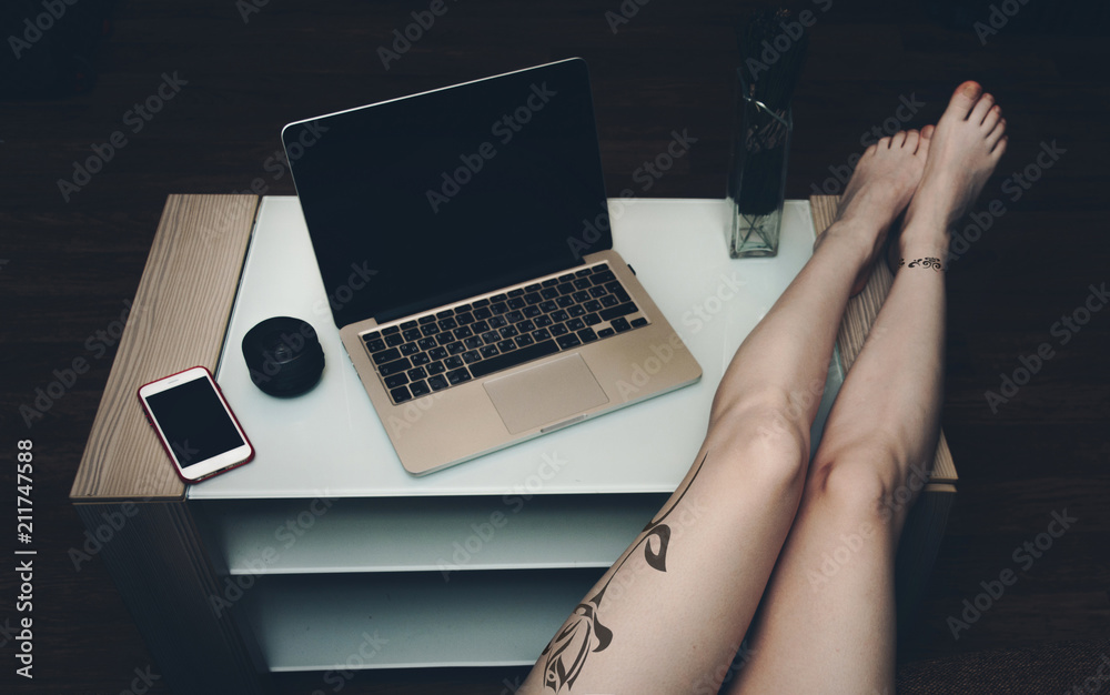 Sexy women's feet with tattoos on the table with laptop. foto de Stock |  Adobe Stock