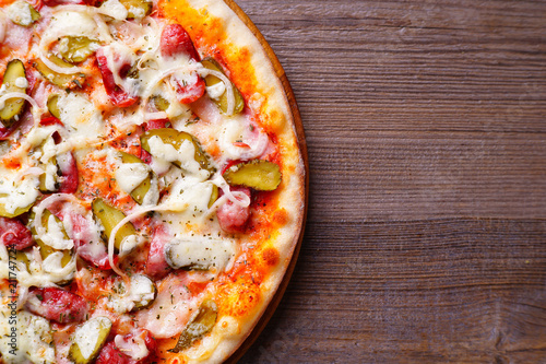 Classical Napoli pizza with salami and gherkins  popular Italian snack close up with copy space. Restaurant  food delivery  pizzeria menu concept.