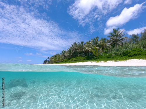 HALF UNDERWATER: Summer sun shines on calm turquoise ocean and tropical beach.