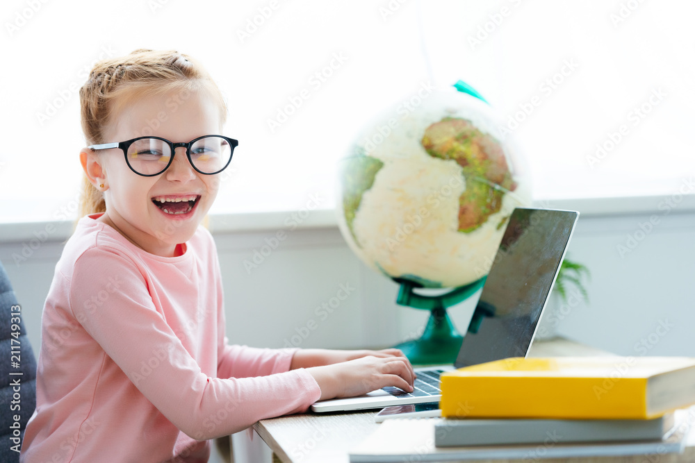 adorable happy schoolchild in eyeglasses studying with laptop and books at home adorable happy schoolchild in eyeglasses studying with laptop and books at home