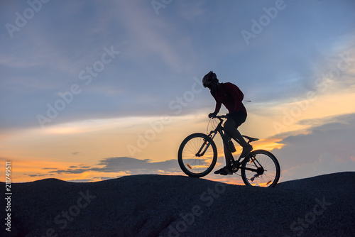 Fototapeta Naklejka Na Ścianę i Meble -  silhouette of a man riding a mountain bike up a hill, extreme sport mountain biker