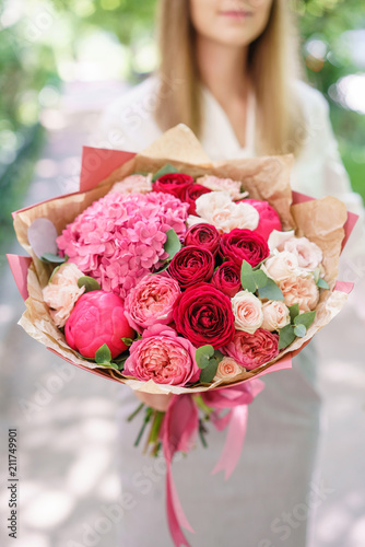 Beautiful summer bouquet. Arrangement with mix flowers. Young girl holding a flower arrangement with hydrangea. The concept of a flower shop. Content for the catalog