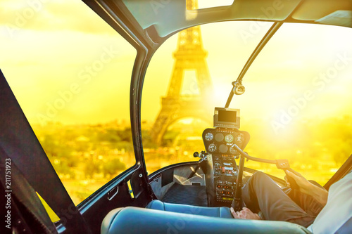 Helicopter cockpit interior flying on Tour Eiffel at sunset in Paris, France. Travel and tourism concept. Scenic flight above Paris skyline. Urban sunset aerial scene on blurred background. © bennymarty