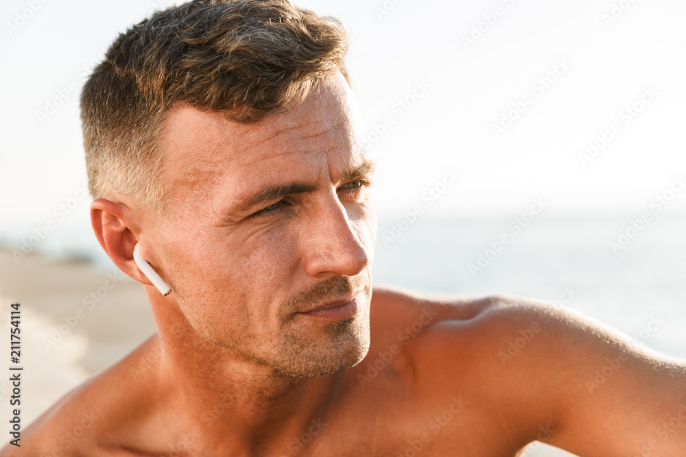 Obraz premium Close up of handsome shirtless sportsman with earphones