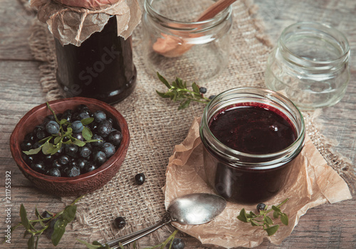 Homemade Blueberry jam in jar with berries and leaves over rustic wooden table