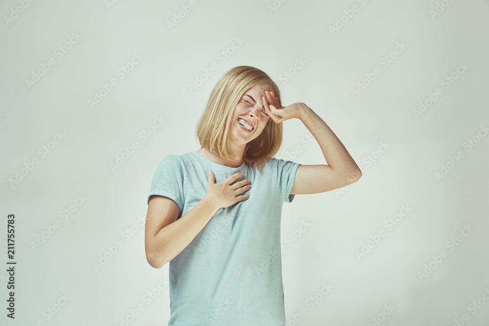 The happy freckled woman standing and smiling against gray background. The happy freckled woman standing and smiling against gray background.