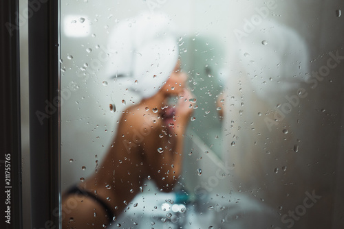 Woman through steamy glass in bathroom