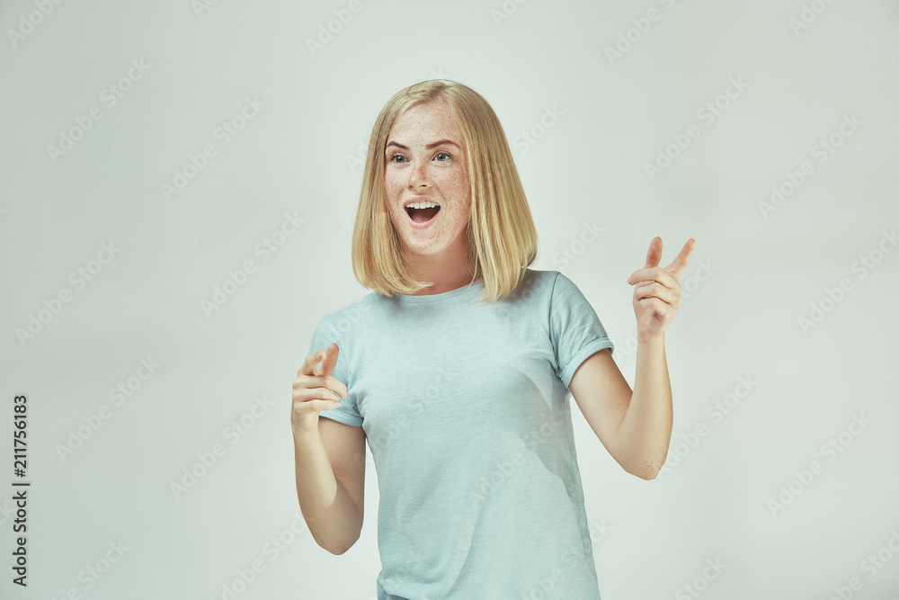 Fototapeta premium The happy freckled woman standing and smiling against gray background.