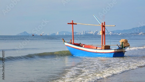 The old fisherman boat on the sea with blue sky and white cloud in the morning summer.