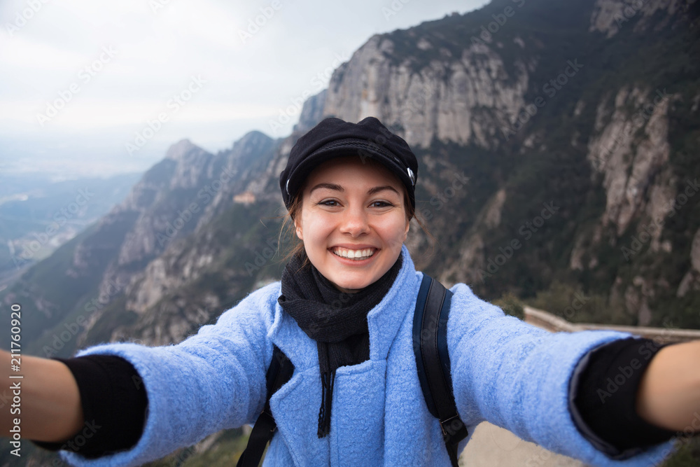 Pretty young female tourist makes selfie in Mountain Monserrat,Spain.Woman traveler taking selfie in mountains Travel Lifestyle adventure concept active vacations outdoor 