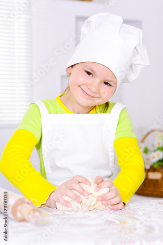 Wallpaper Mural Cute little girl in chef's hat baking cake in the kitchen  Torontodigital.ca