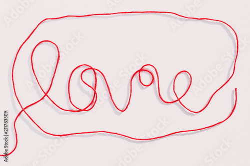 Word love written with red wool thread isolated on white background. Horizontal view.