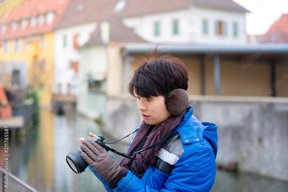 portrait of Asian man Tourist travelling with digital camera in a ribeauville town, colmar, france - one of the oldest medieval town in Alsace.