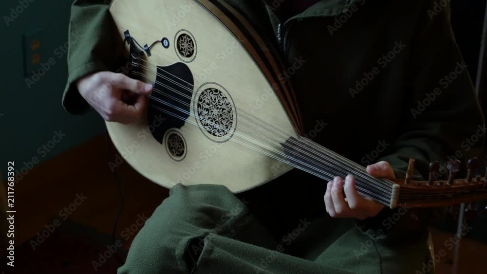 Closeup of oud while a musician plays music on it.