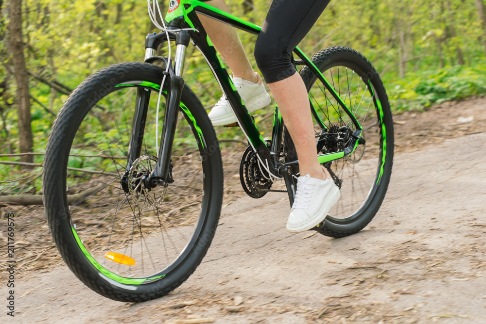 Fototapeta premium Young woman in a sport bike suit with a bicycle in the park. Health and relaxation.