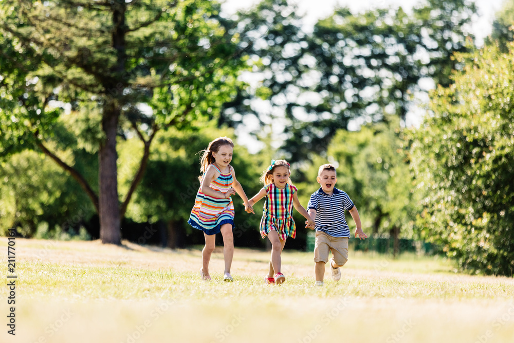 Fototapeta premium Three happy kids holding hands and running