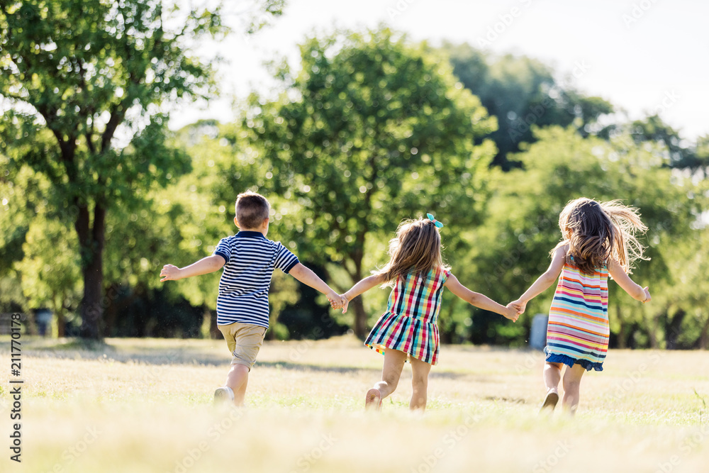 Fototapeta premium Troje małych dzieci biegających po zielonym polu