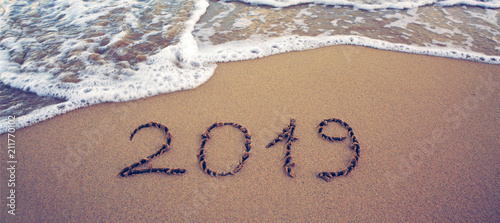Year 2019 written at the caribbean sand beach with sea wave .