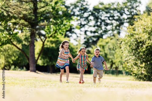 Three happy kids holding hands and running