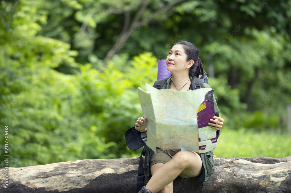 Naklejka premium the tourist Middle-aged woman in a backpack with a backpack. See the map on a wooden stick