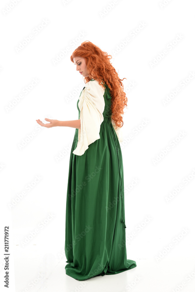 full length portrait of red haired girl wearing long green medieval gown. standing pose, isolated on white studio background.