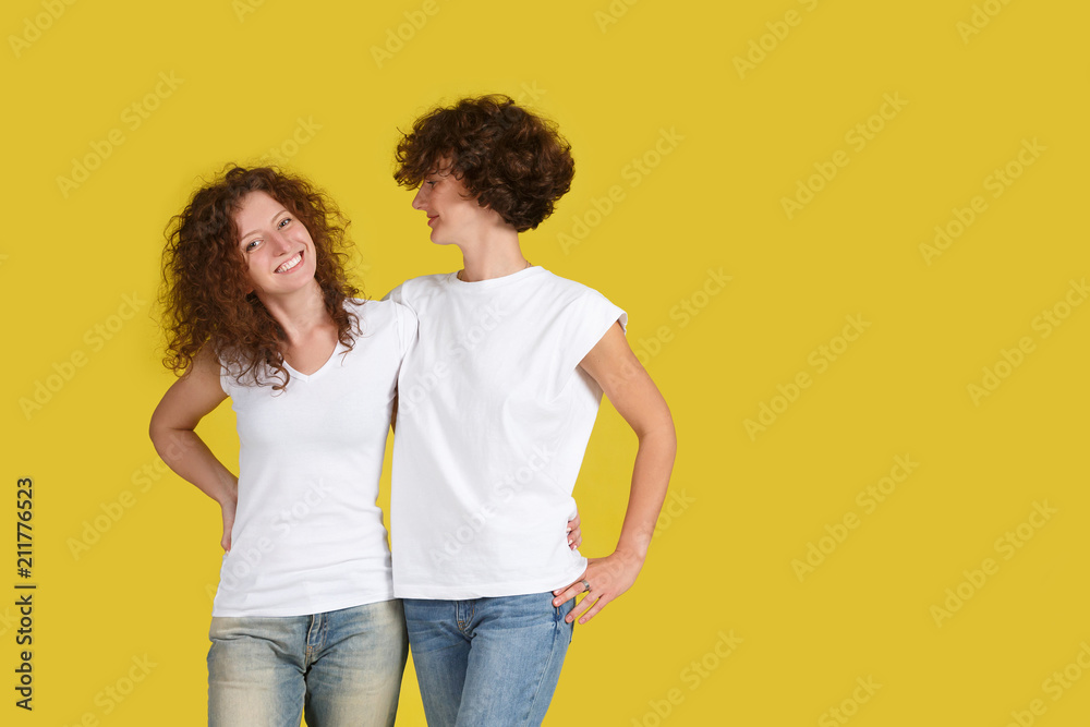 Horizontal shot of beautiful female and her younger sister embraced, love each other against of yellow studio background. Family relationships concept care. Two woman with shaggy hair. Copyspace Horizontal shot of beautiful female and her younger sister embraced, love each other against of yellow studio background. Family relationships concept care. Two woman with shaggy hair. Copyspace
