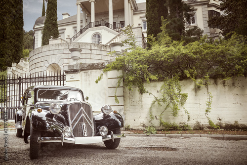 Coche negro de epoca años 20 aparcado al lado de un palacete