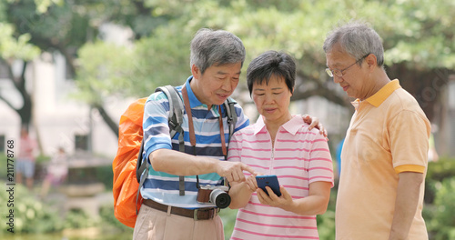 Senior old male friends chatting together at outdoor park, showing photo on cellphone to other © leungchopan