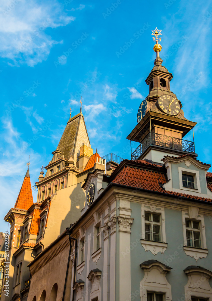 Fototapeta premium Clocks and spire with hebrew on the Jewish Town Hall in Josefov quarter of town. Tower and roof of High synagogue in Prague, Czech Republic
