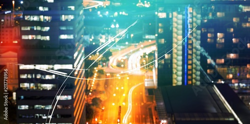 Glowing road amidst building in city at night photo