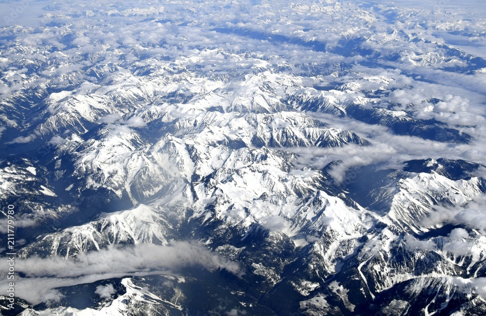 aerial view above the clouds looking at snow capped  Mountain Ranges in British Columbia near Fraser Valley, Canada