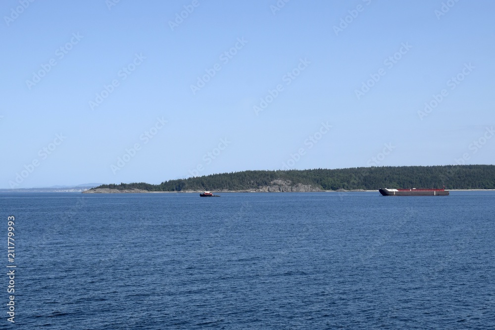 industrial ship guided by a pilot boat in the waters of the Strait of Georgia near Harwood Island,  British Columbia Canada 