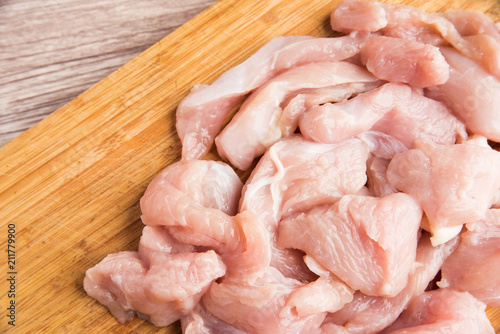 Sliced fresh chicken fillets on a wooden cutting board