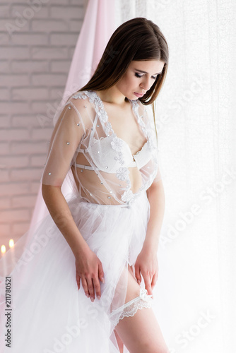 beautiful girl bride in a white lace boudoir dress linen closed with a veil on the wedding day morning on the beautiful scenery of flowers.